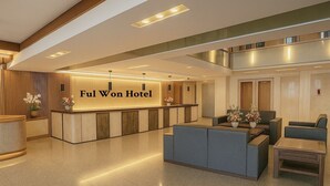 A hotel reception area with a reception desk, seating area, and a staircase leading to an upper level. - Ful Won Hotel (Taichung)