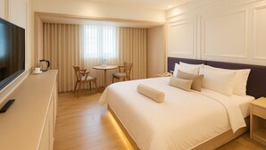 A hotel room with a large bed, a TV, a desk with a coffee maker, and a small table with chairs. - Ful Won Hotel (Taichung)