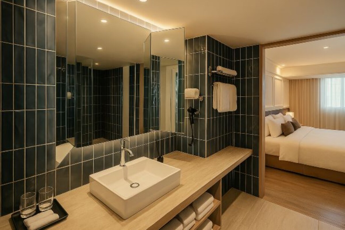 A modern bathroom with a large mirror, a white sink, and a wooden vanity.