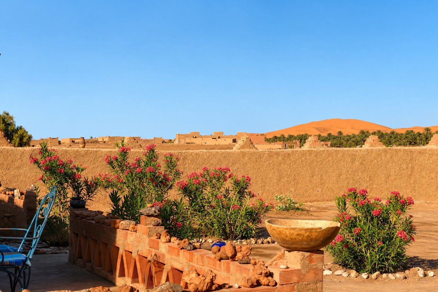 Un paysage désertique avec des bâtiments traditionnels, un ciel dégagé et une chaise bleue.