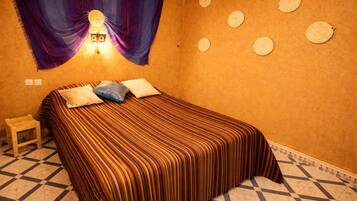 A room with a bed, a nightstand, a wall-mounted light, and decorative plates on the wall.