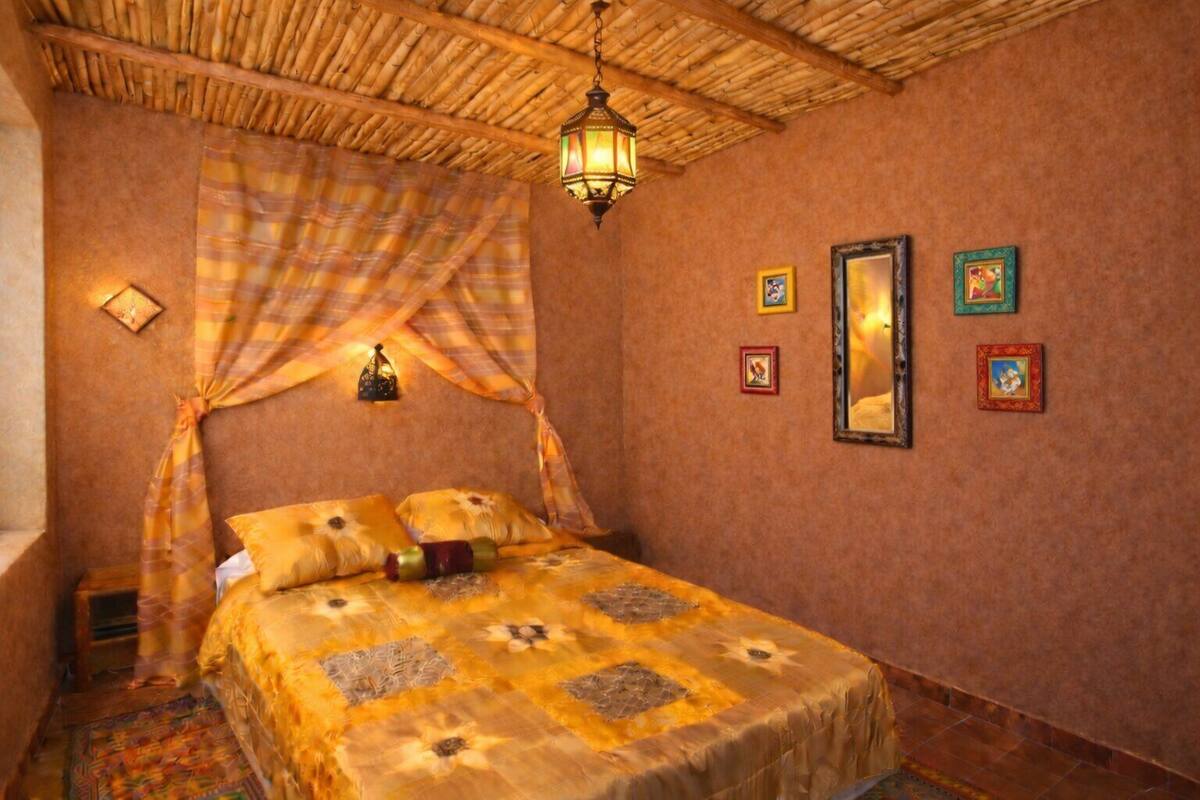 Una habitación con una cama, un farol colgante y una pared adornada con cuadros.