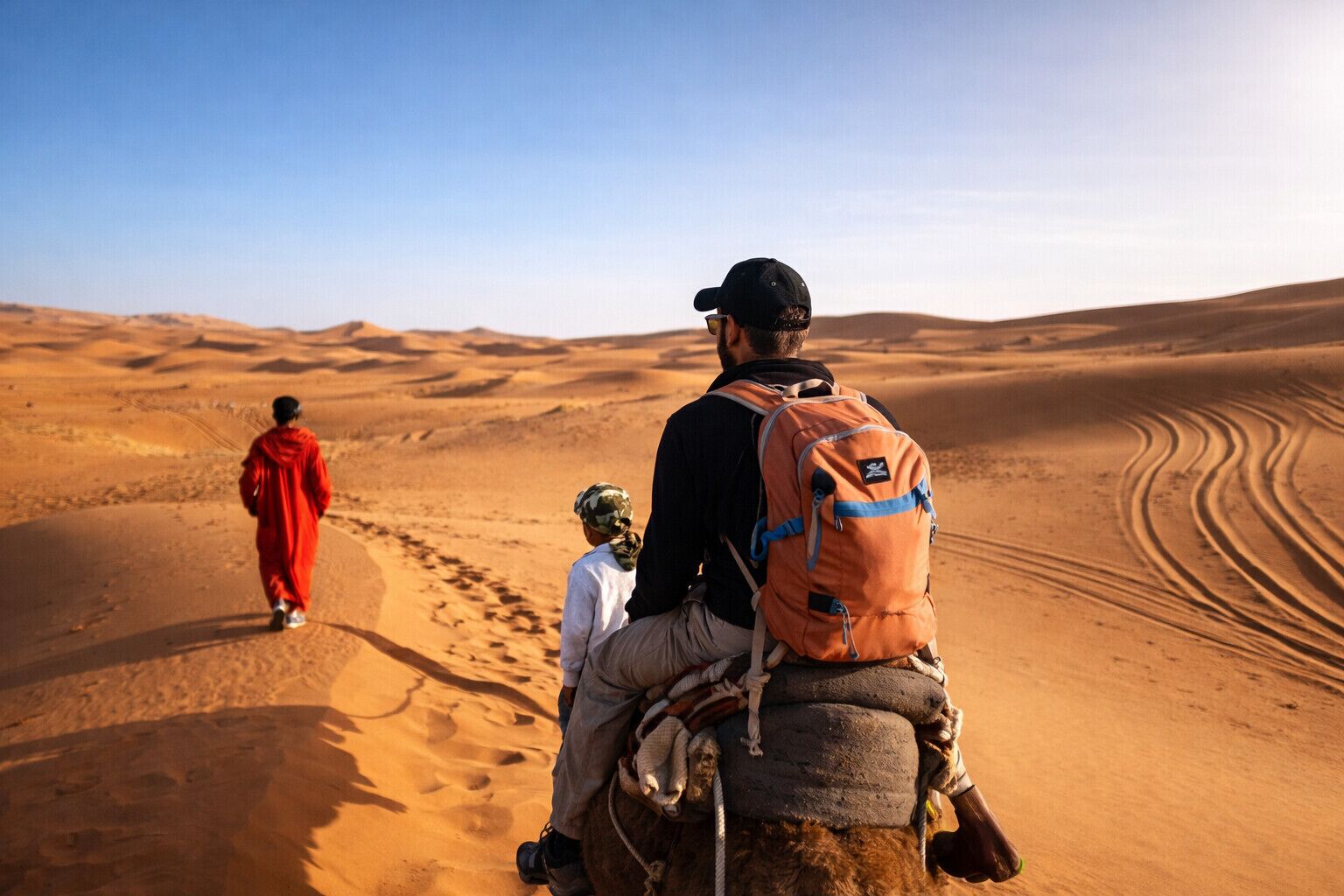 A desert landscape with sand dunes and a person riding a camel.
