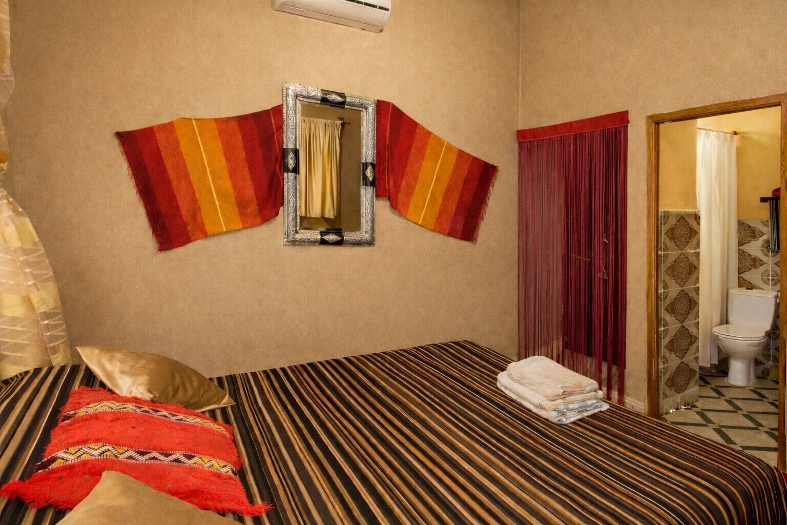 A hotel room with a bed, a mirror, and a bathroom visible through an open door.