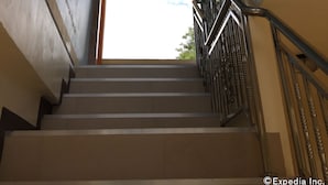 A staircase with a metal railing leading to a door with a view of the sky. - Gemini Hotel & Restaurant (Panglao)