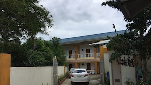 A residential house with a car parked in the driveway, surrounded by greenery and a gated entrance. - Gemini Hotel & Restaurant (Panglao)