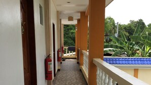 A corridor with a tiled floor, white walls, and a balcony with a blue roof. - Gemini Hotel & Restaurant (Panglao)