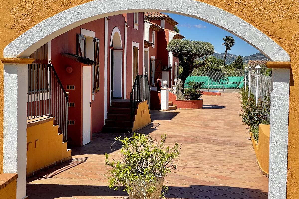 Un patio con un edificio rojo, una escalera y una planta en maceta.