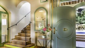 A staircase with a railing, a door with a circular handle, and a small table with a potted plant. - Hotel La Romarine (Ramatuelle)