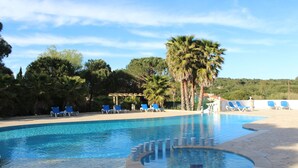 A swimming pool with blue chairs and palm trees. - Hotel La Romarine (Ramatuelle)
