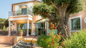 A two-story building with a balcony, a staircase leading to the entrance, and a large tree in the foreground. - Hotel La Romarine (Ramatuelle)