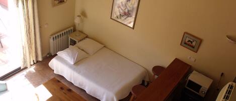 A bedroom with a bed, bedside table, lamp, and a radiator.