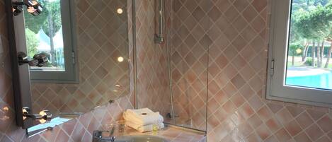 A bathroom with a glass-enclosed shower, a sink, and a bathtub.