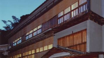 A traditional Japanese building with multiple floors, large windows, and a ground-level entrance with a sign.
