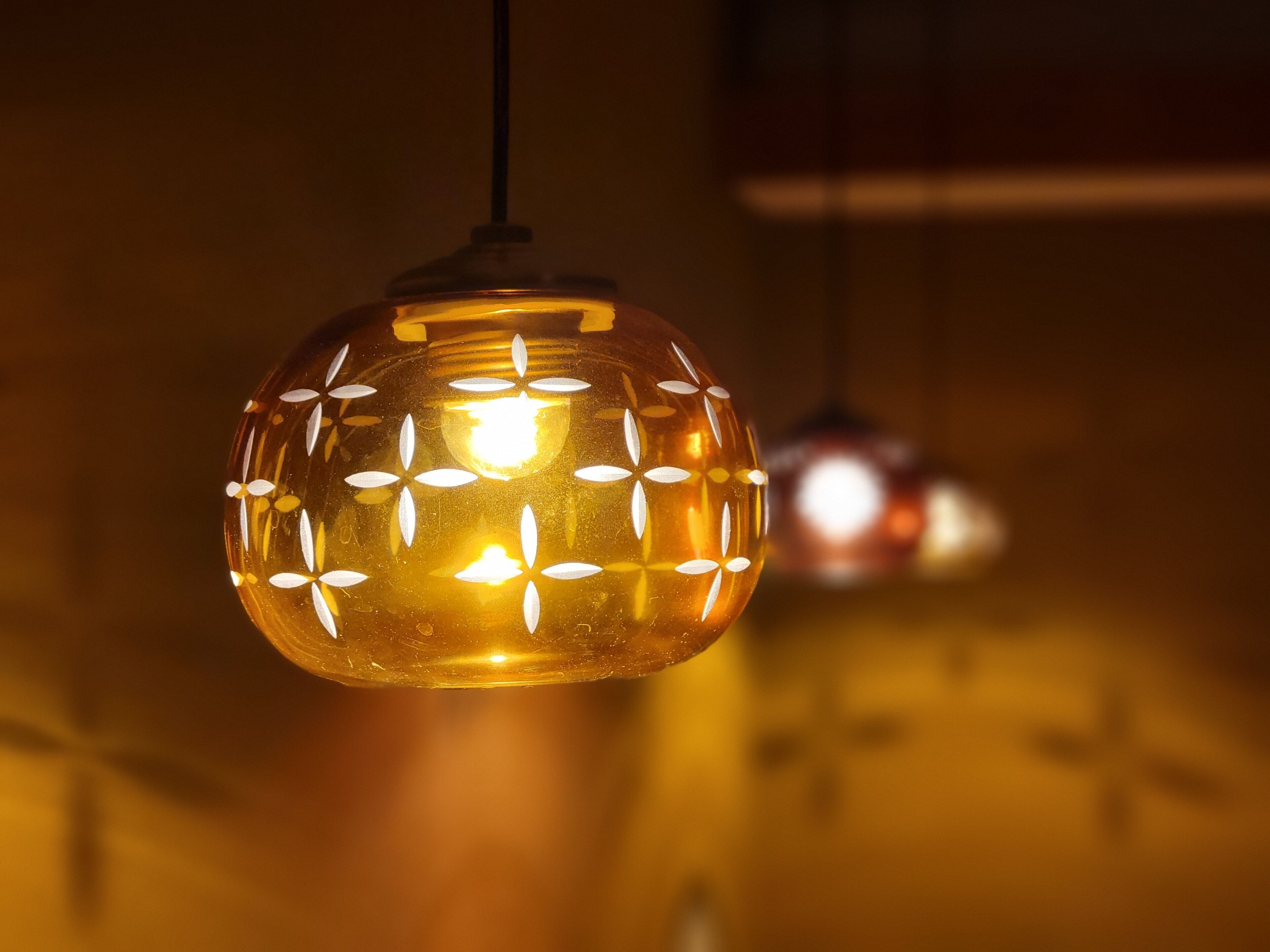 Primer plano de una lámpara colgante esférica con diseño decorativo, suspendida del techo.