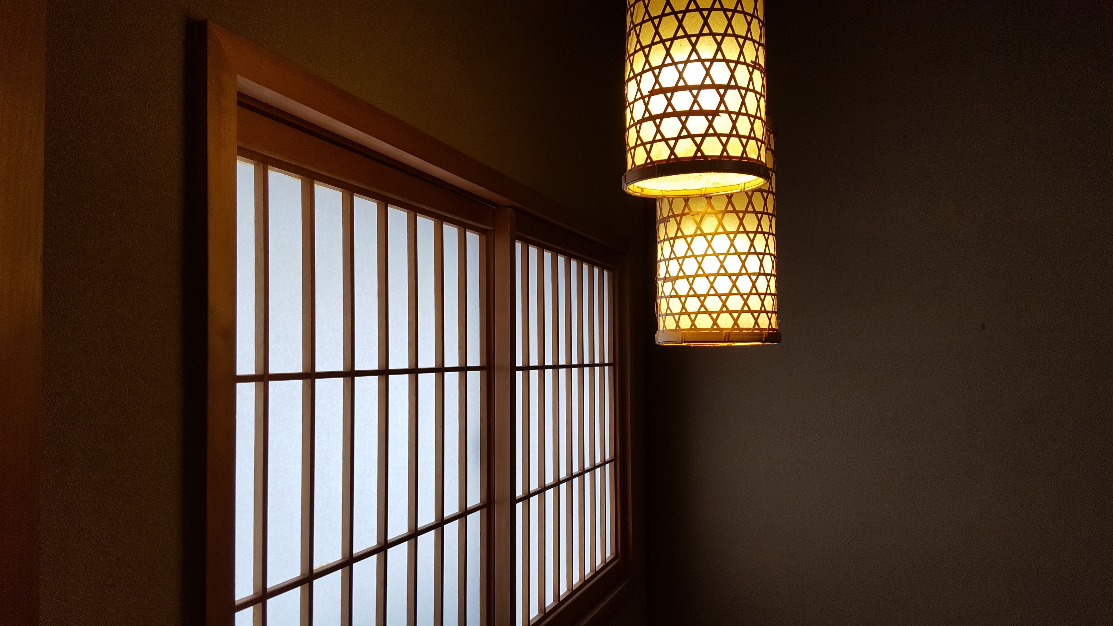 A traditional Japanese-style room with sliding shoji doors and a hanging paper lantern.