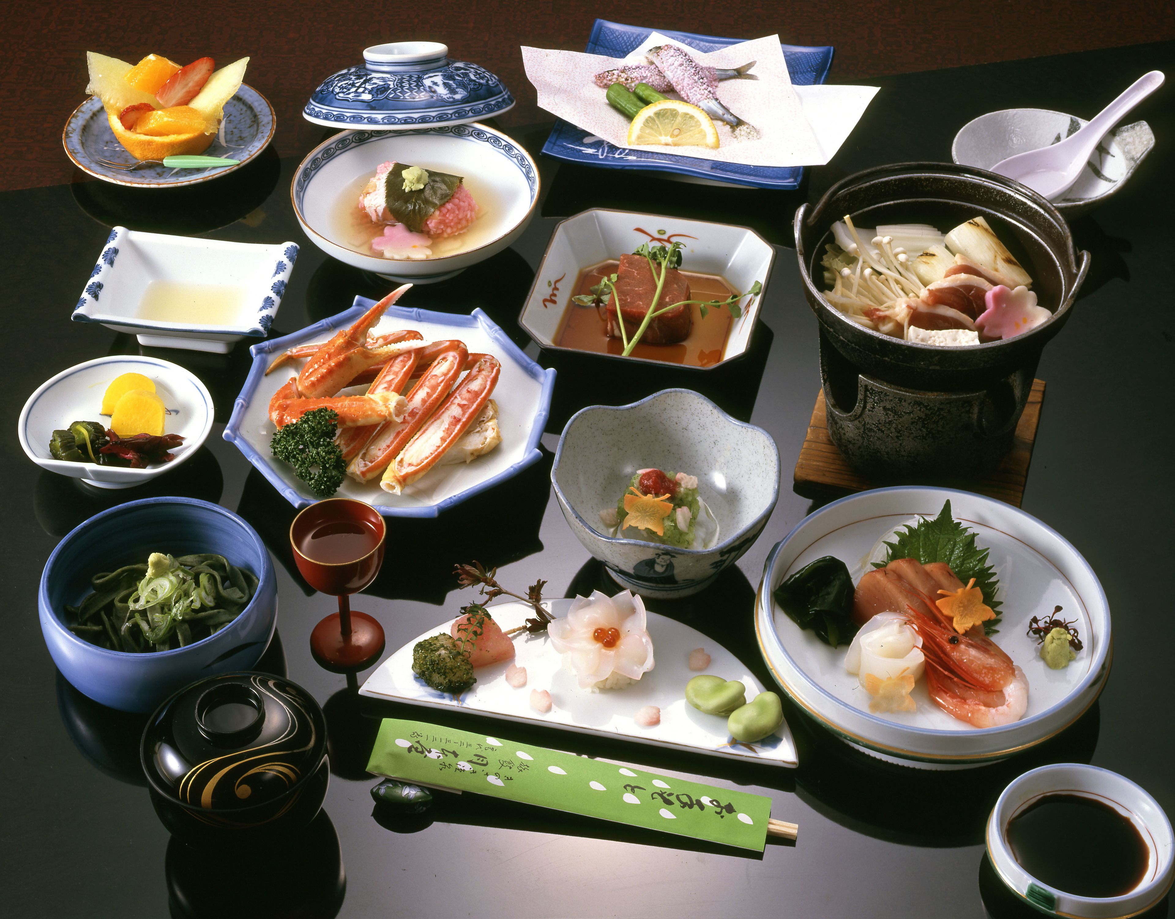 A variety of Japanese dishes arranged on a table, including seafood, vegetables, and rice.