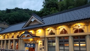 Ein traditionelles japanisches Gebäude mit einem Ziegeldach, einem Schild mit der Aufschrift „ICHINOUYU BATH“ und einer Tafel mit japanischen Schriftzeichen.
