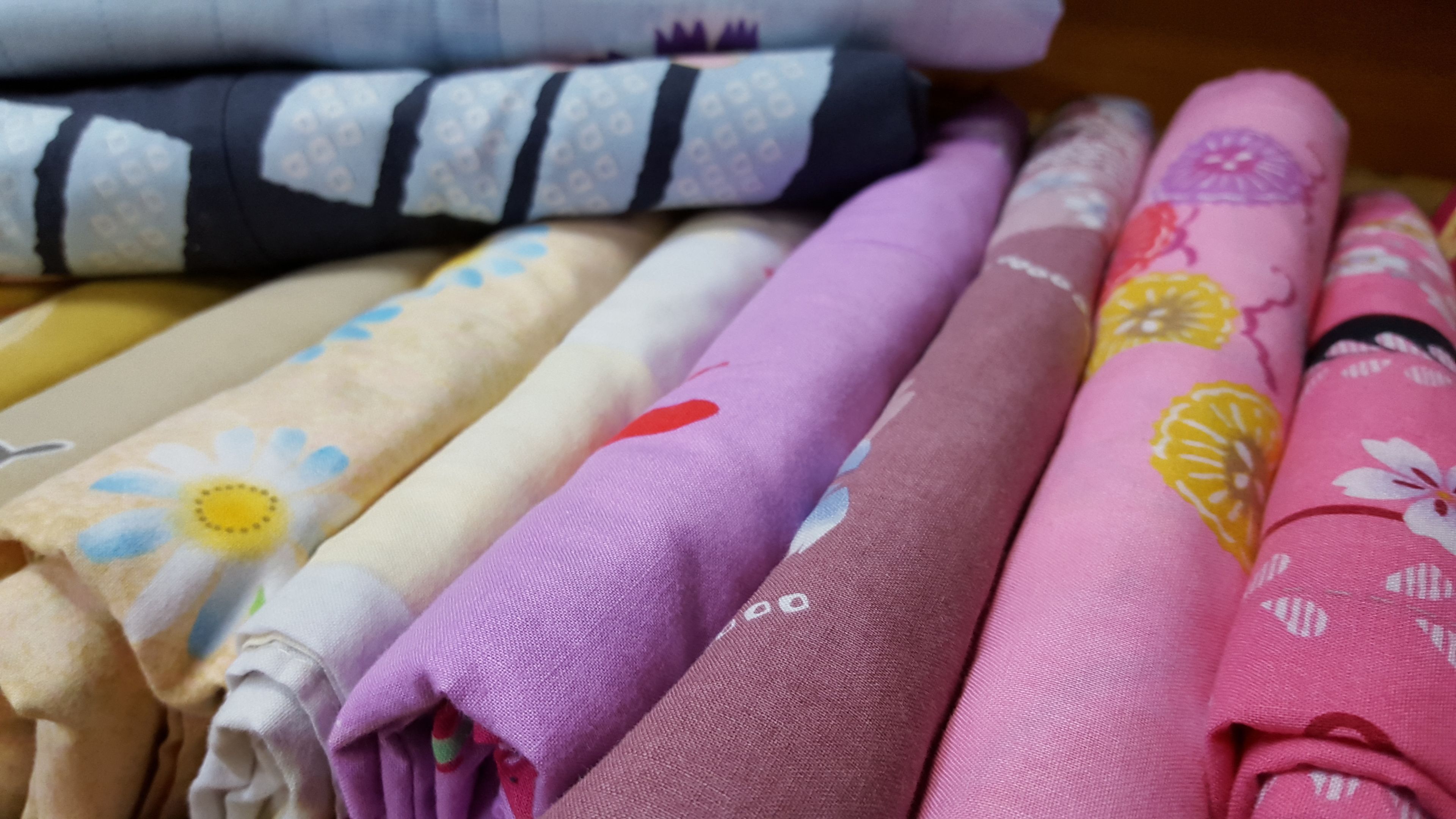A variety of folded fabrics with different patterns and colors.