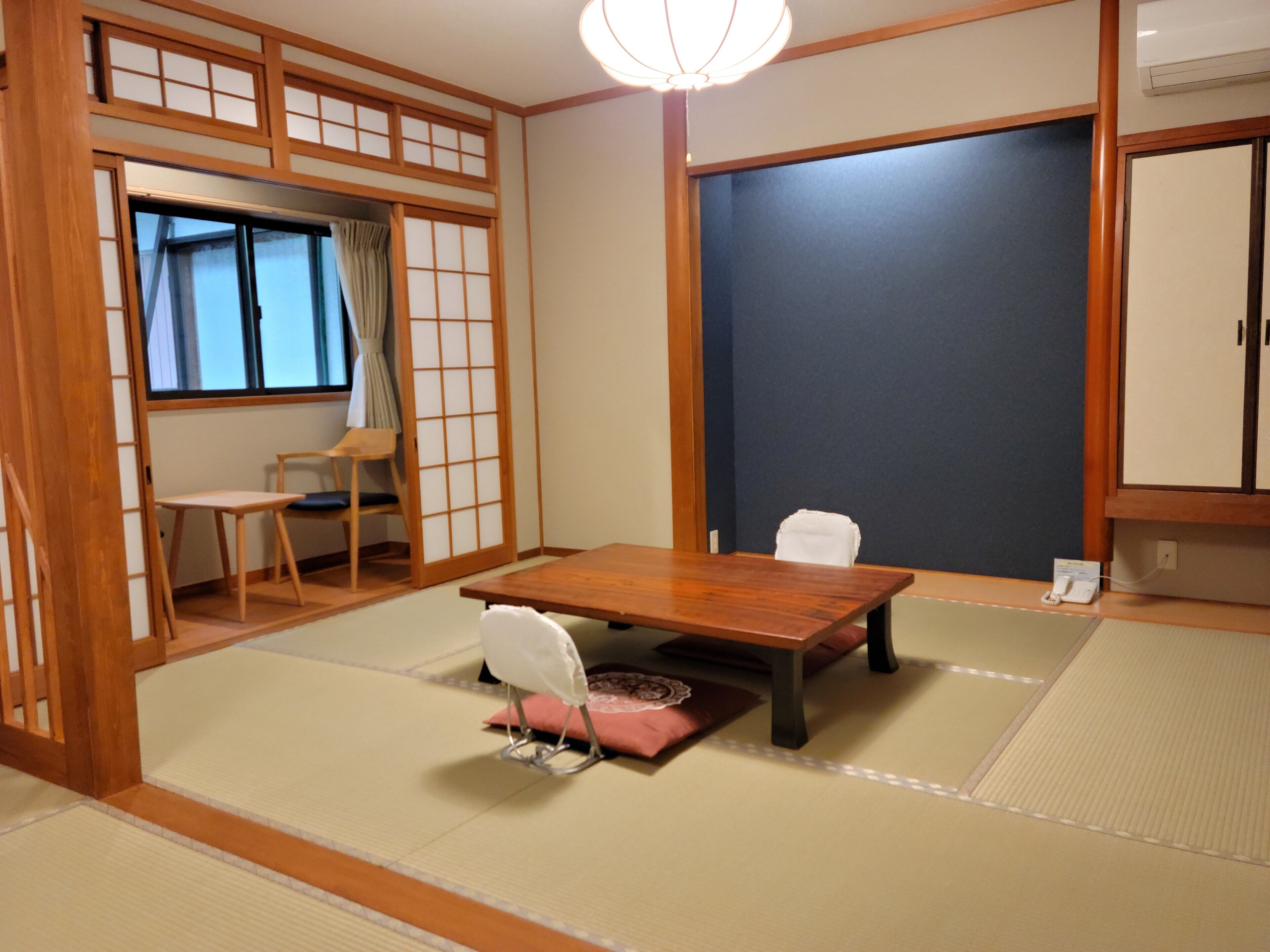 A traditional Japanese room with tatami flooring, a wooden table, and a sliding door.