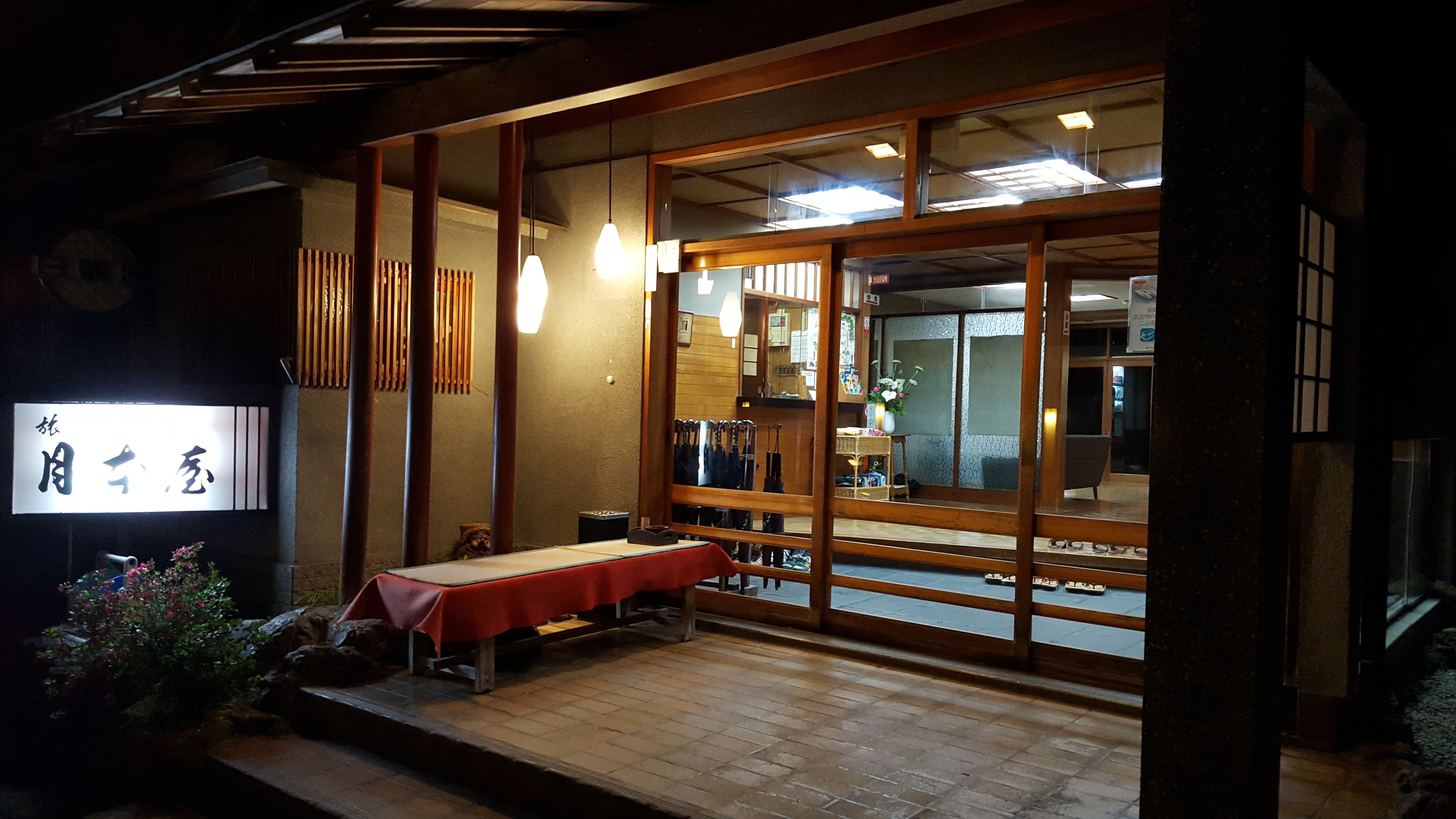 A traditional Japanese restaurant with a wooden exterior, a table with a red tablecloth, and a sign with Japanese characters.