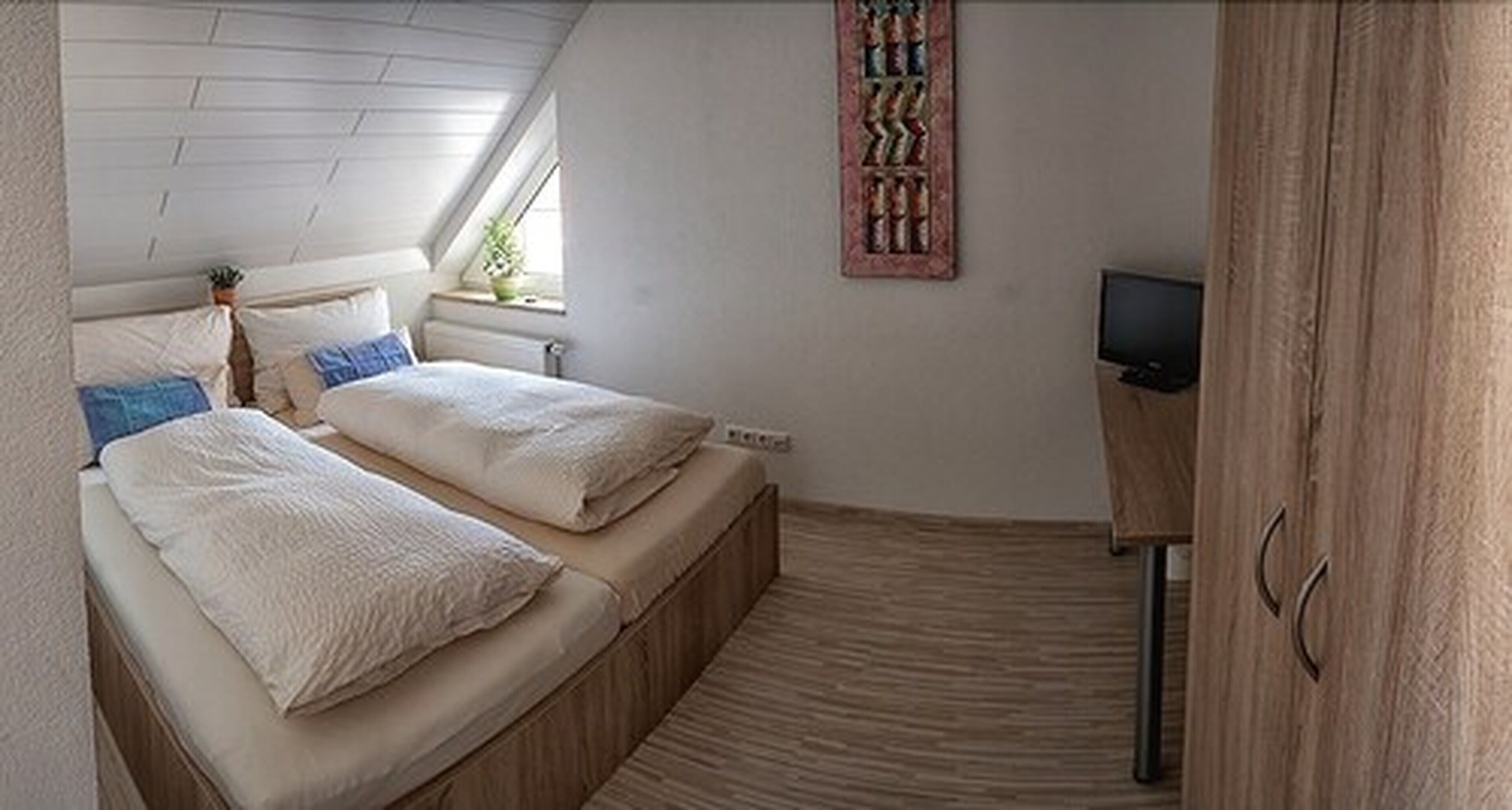 Een slaapkamer met twee bedden, een televisie en een raam.