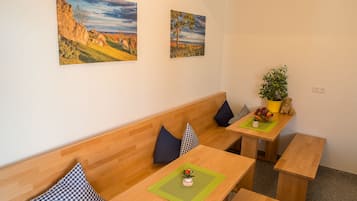 Une pièce avec un banc en bois, une table sur laquelle est posée une plante, et deux tableaux accrochés au mur.