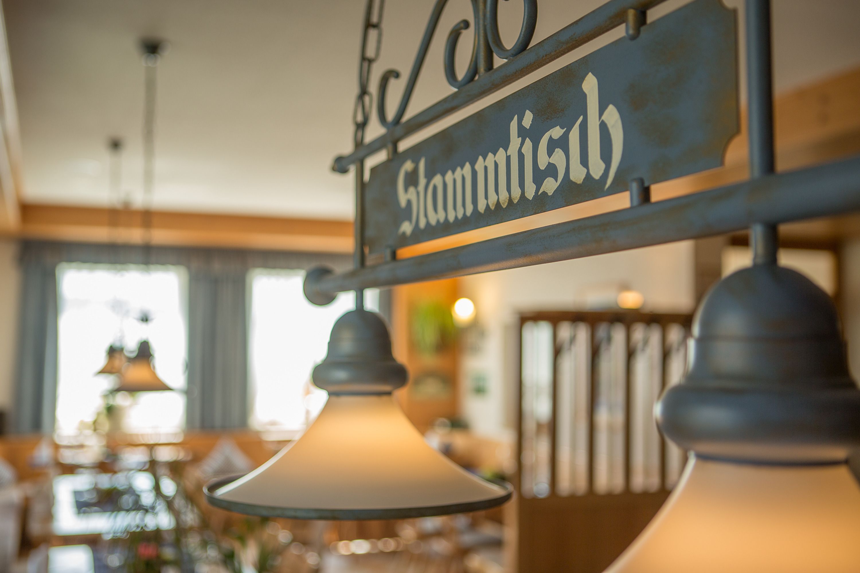 Ein hängendes Schild mit dem Namen "Stammtis" in rustikalem Metalldesign.