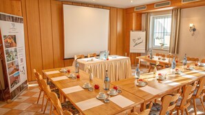 Un salón de conferencias con paneles de madera, una pizarra grande y una mesa dispuesta para una reunión.