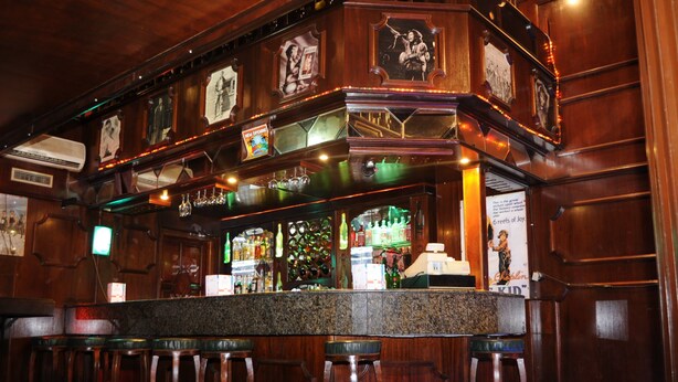 A bar area with wooden decor, a counter, and bar stools. - Royal Beach (Sousse)