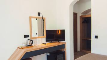 A bedroom with a desk, a television, a mirror, a bed, and a wardrobe.