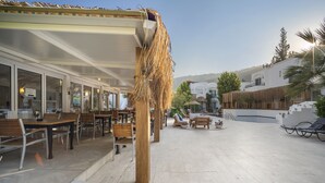 An outdoor seating area with tables and chairs, a thatched structure, and a view of the surrounding buildings and landscape. - Costa Sariyaz Hotel (Bodrum)