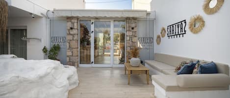 A hotel entrance with a stone facade, a wooden bench, and a beige sofa.
