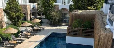 Área de piscina com piscina azul cristalina, espreguiçadeiras e guarda-sóis.