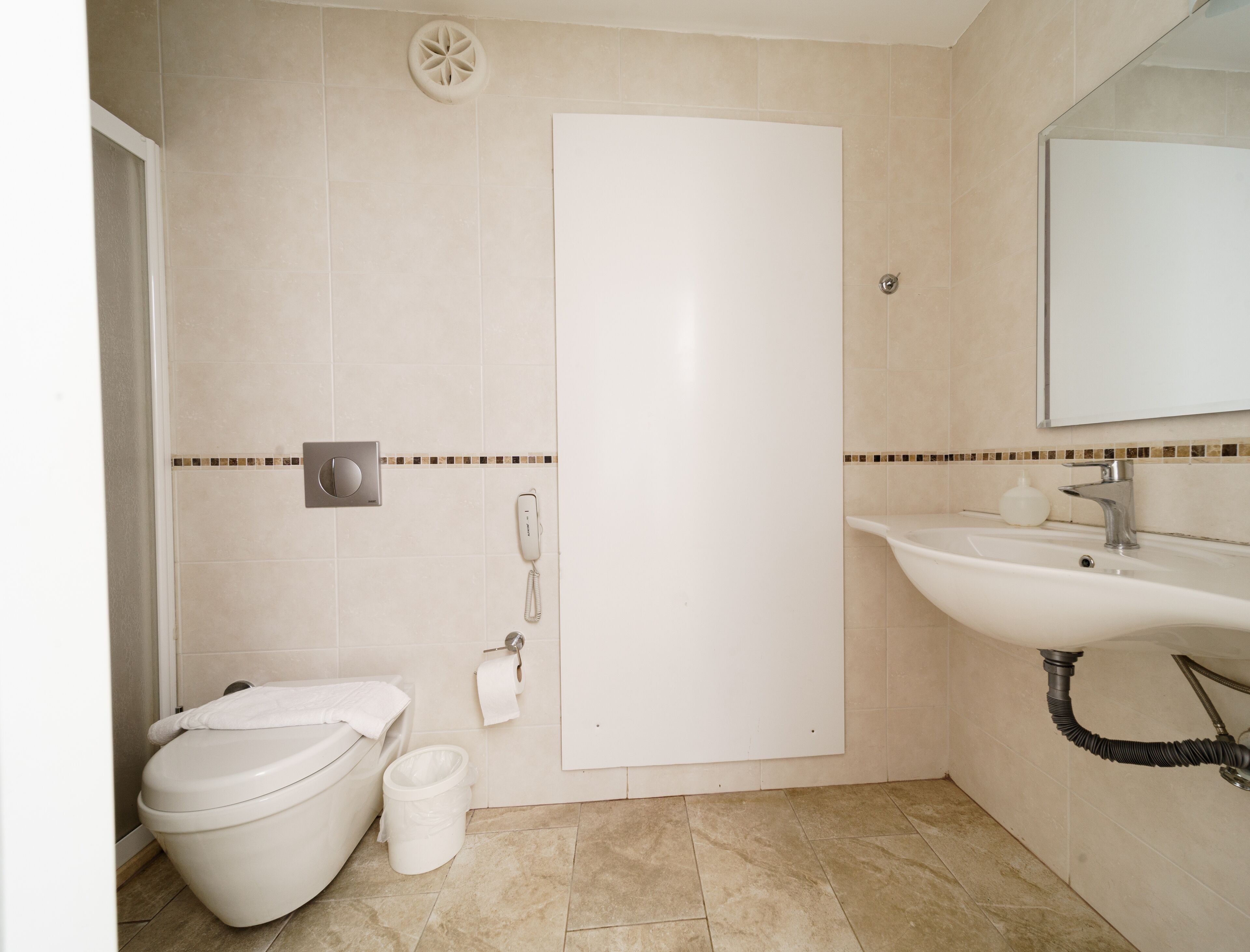 A bathroom with a toilet, bidet, sink, and mirror.