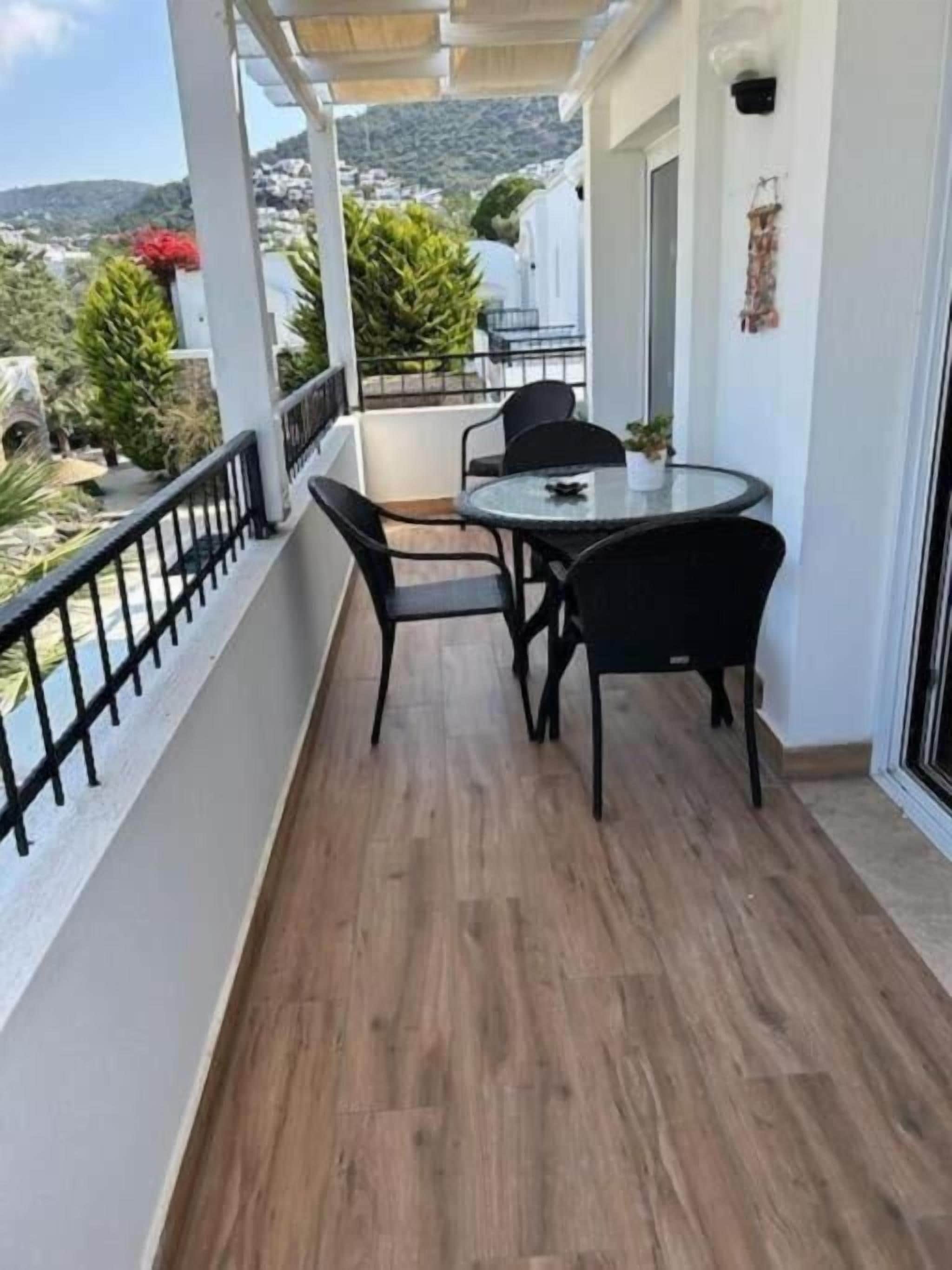 Ein Balkon mit Tisch und Stühlen, einem Geländer und Blick auf die Landschaft.