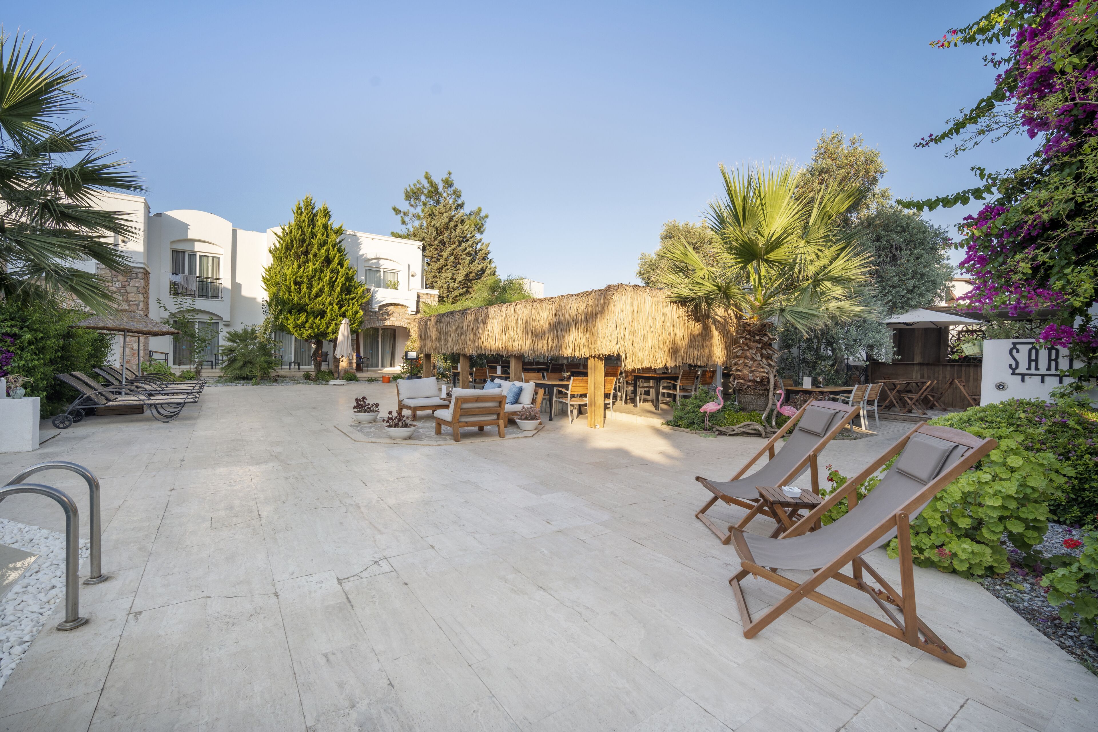 A courtyard with lounge chairs, a thatched-roof structure, and a sign reading "SABU".