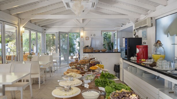 A spacious dining area with a long table filled with various food items and a modern kitchen in the background. - Costa Sariyaz Hotel (Bodrum)