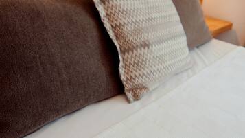 A bed with a wooden headboard, two pillows, and a bedside lamp.