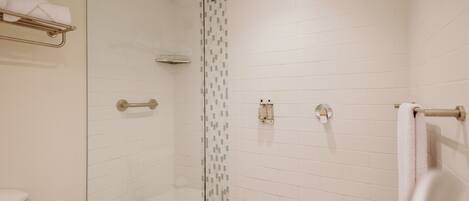 A modern bathroom with a glass shower enclosure, white tiled walls, and a blue-tiled floor.