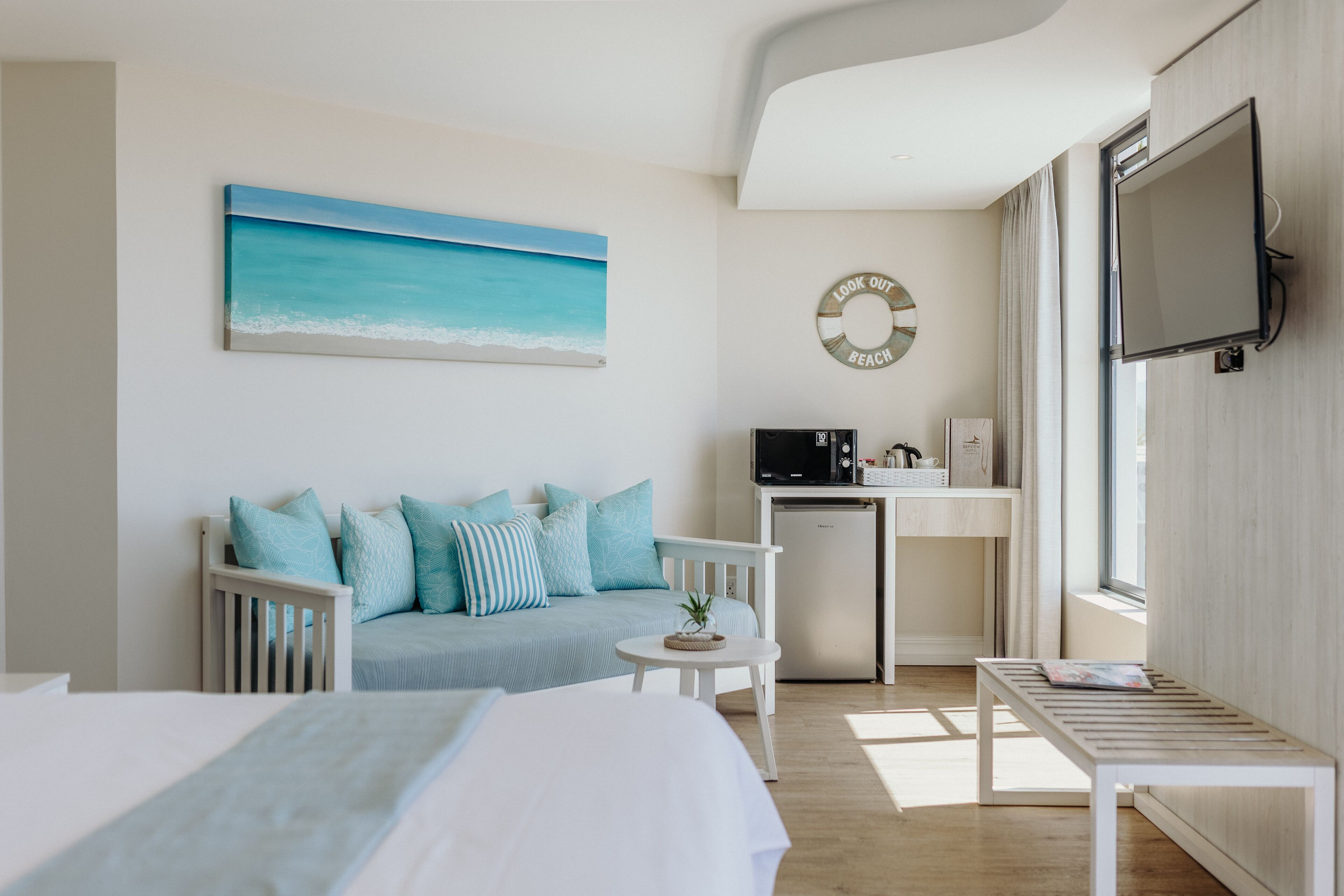 Une chambre d’hôtel moderne équipée d’un lit, d’un canapé, d’une petite table, d’une télévision et d’un coin cuisine.