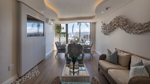Un salon moderne doté d’une grande fenêtre, de meubles en osier et d’un élément décoratif mural.
