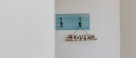 A wall-mounted decoration with a blue plaque and wooden letters spelling "LOVE" suspended by a rope.