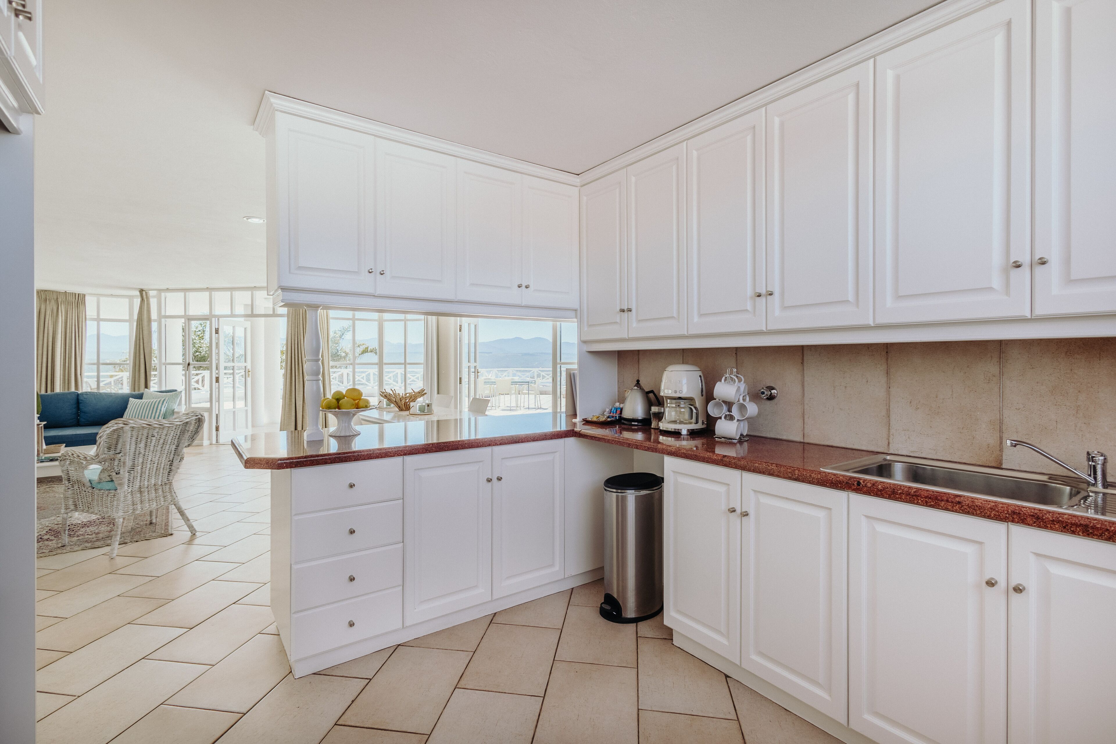 A modern kitchen with white cabinets, a stainless steel sink, and a coffee maker.