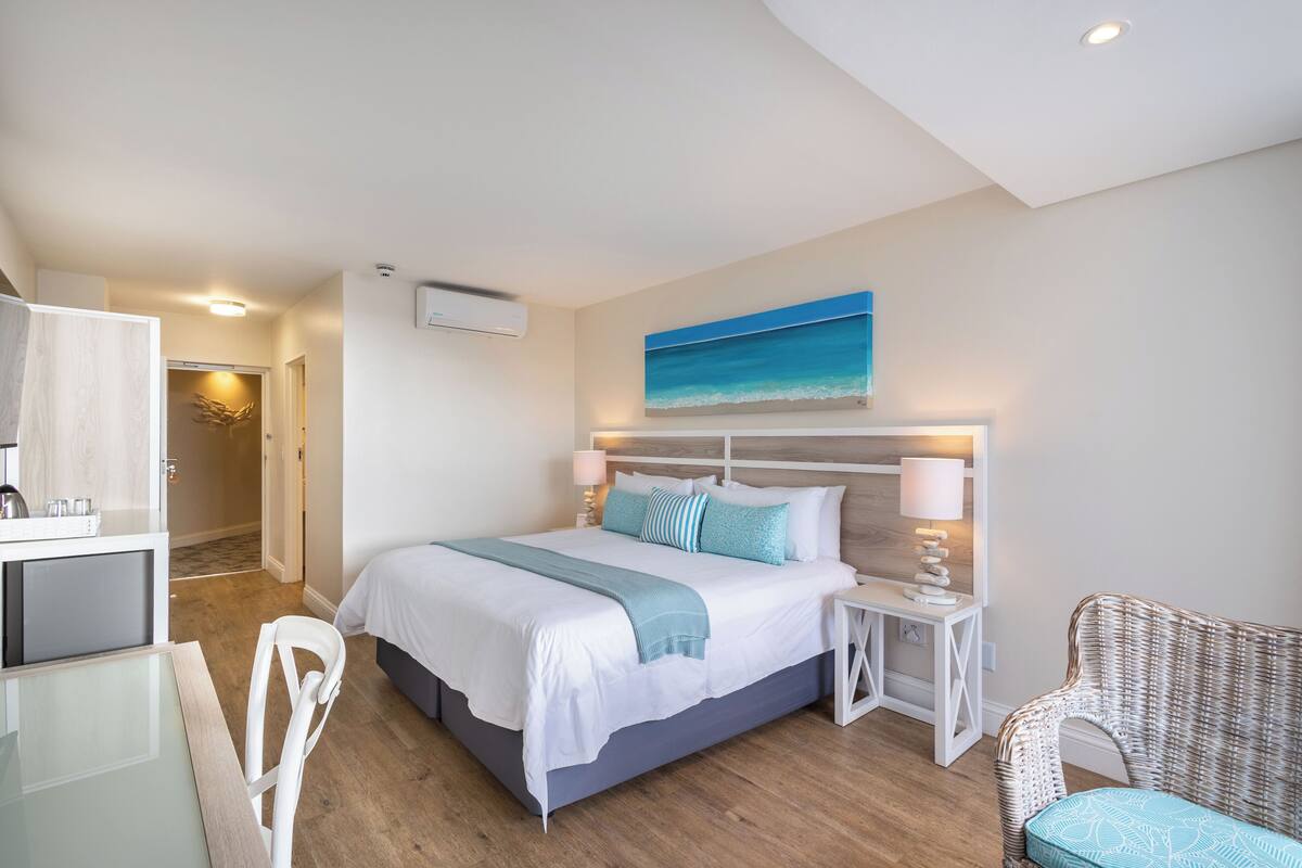 A hotel room with a bed, bedside tables, a chair, and a desk.