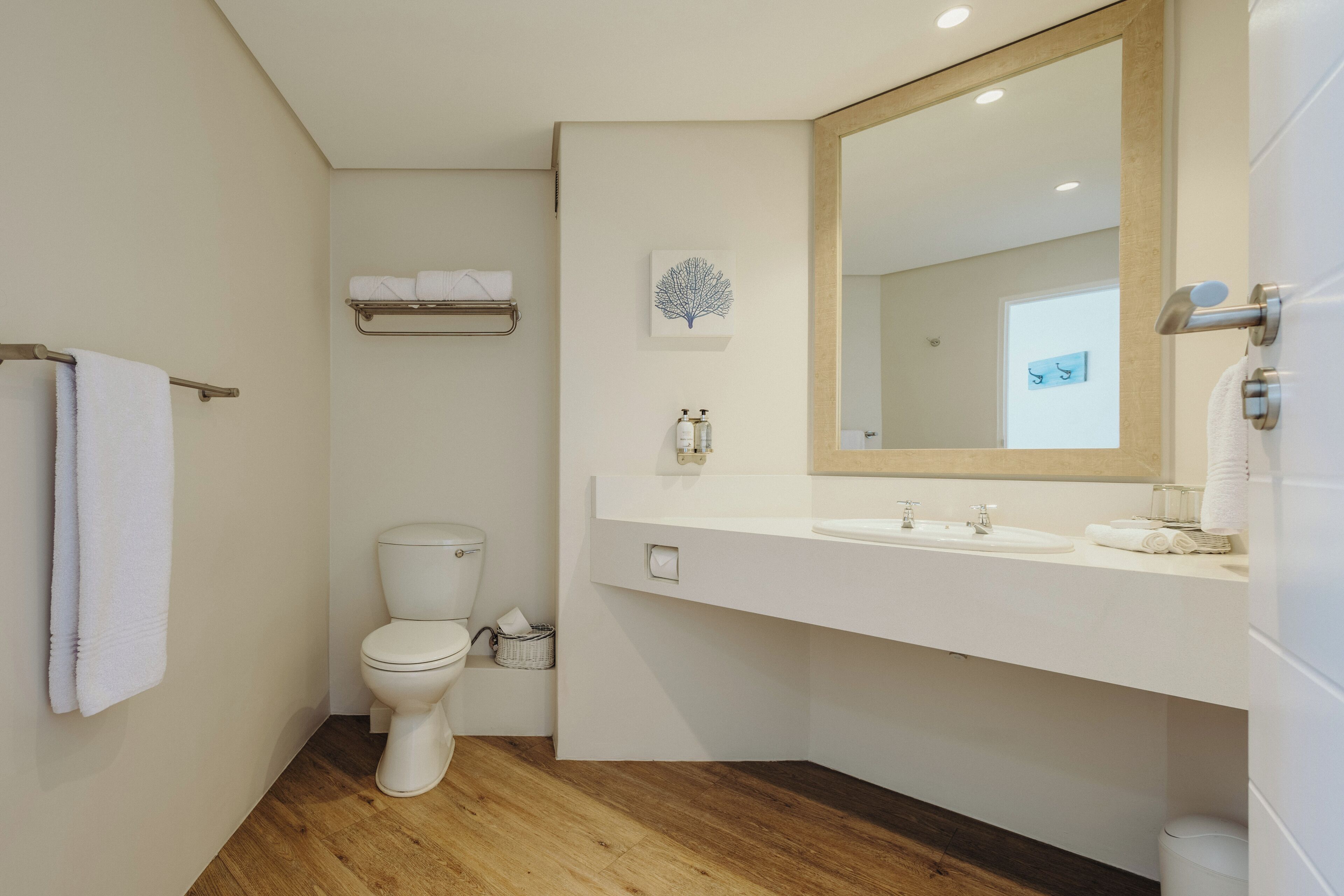 A modern bathroom with a toilet, sink, and mirror.