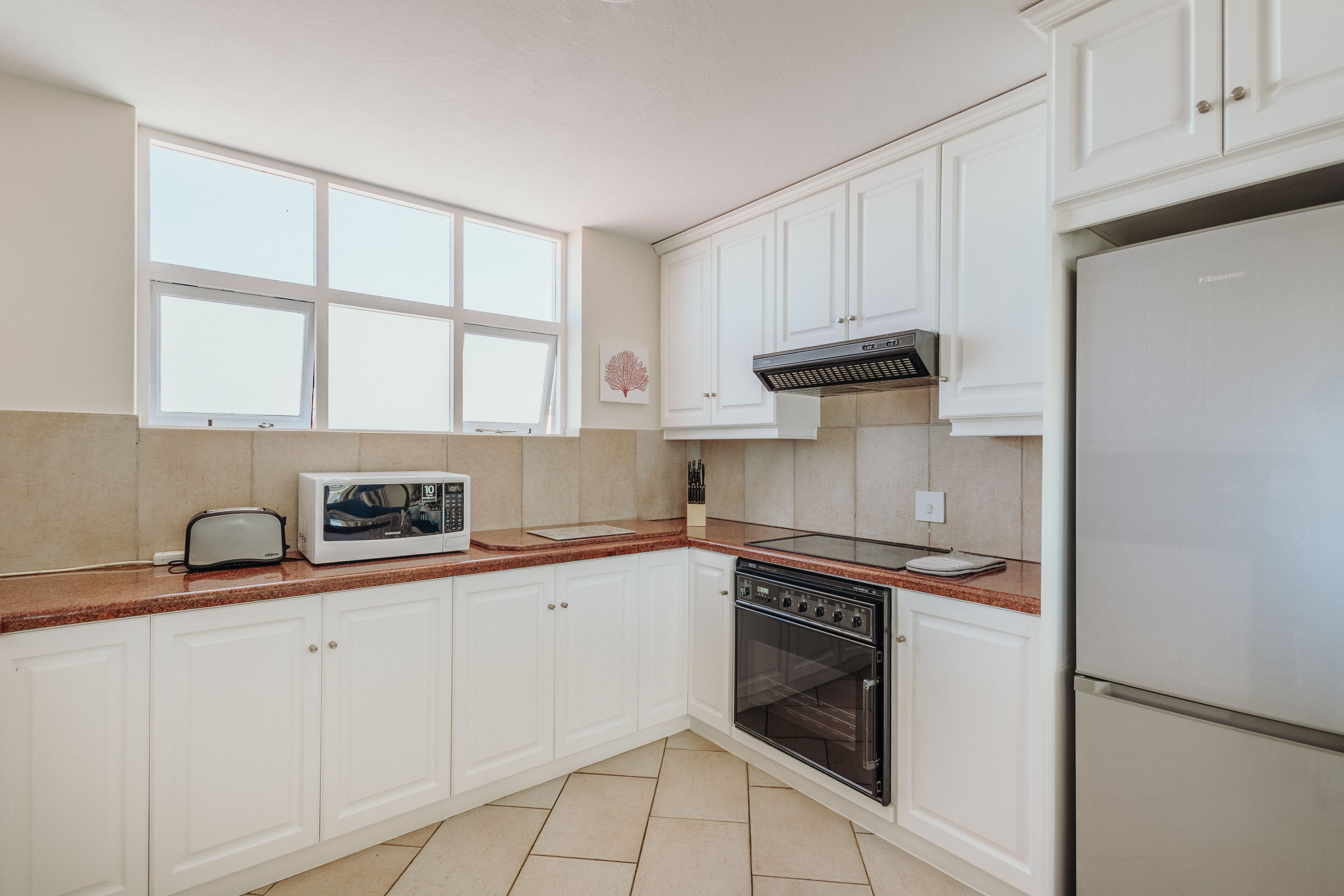 A kitchen with white cabinets, a microwave, a stove, and a refrigerator.