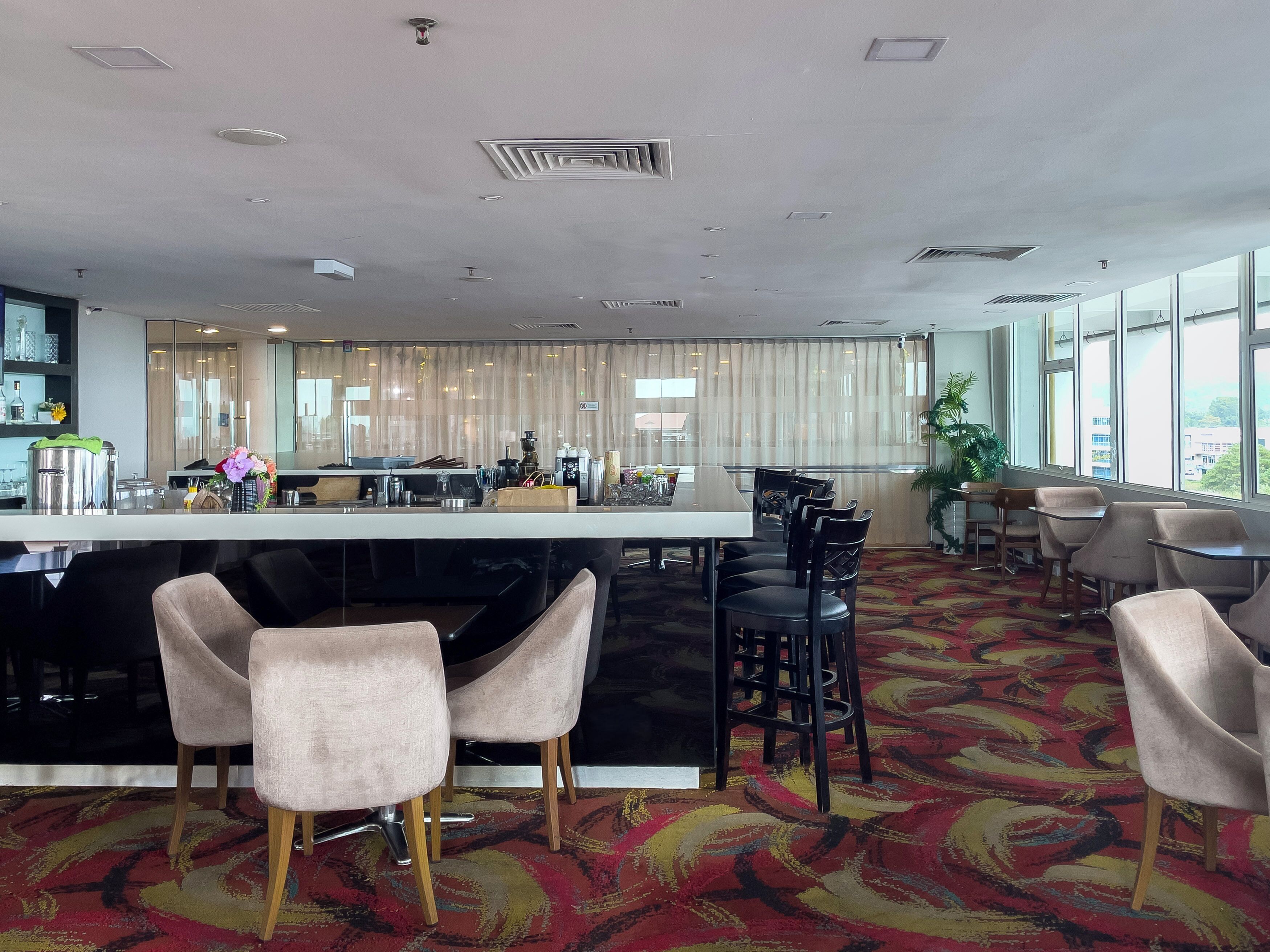 A modern hotel lobby with a bar area, seating, and large windows.