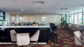 A modern hotel lobby with a bar area, seating, and large windows.