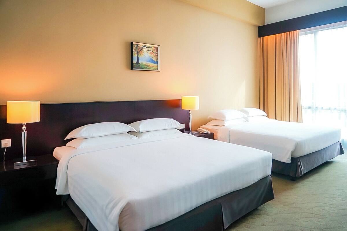Habitación de hotel con dos camas, un cuadro en la pared y una ventana con cortinas.